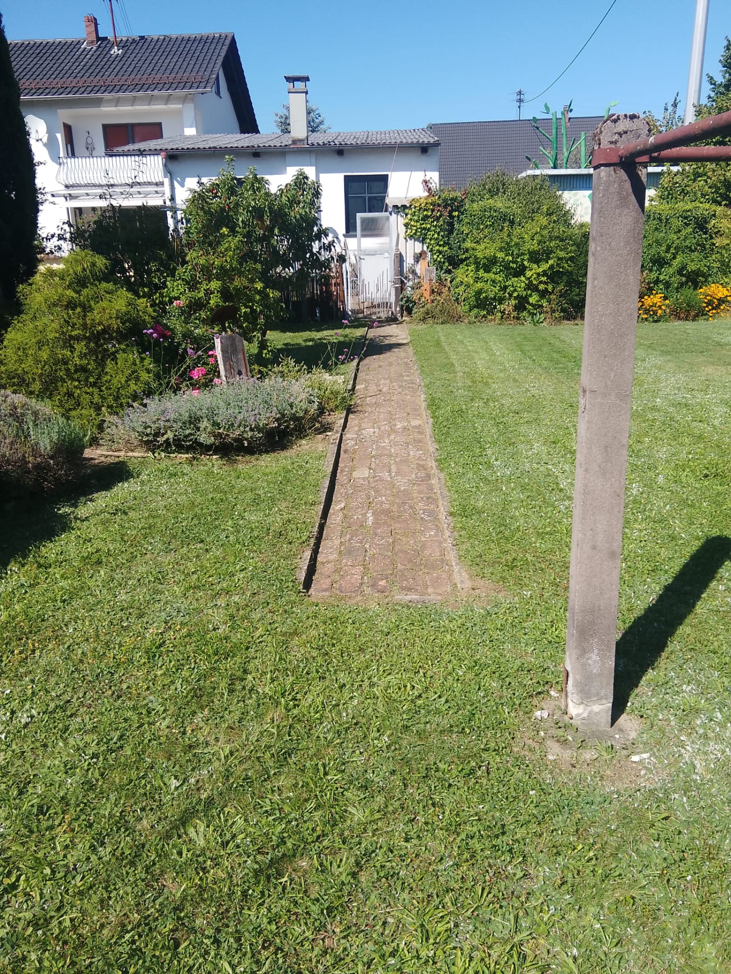 Gepflegter Garten mit kurz geschnittenem Rasen, Beet und Weg