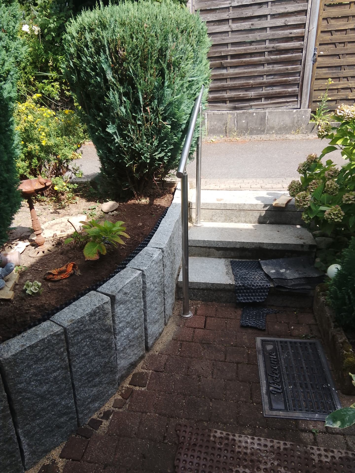 Neugestalteter Garten mit Granitmauer, Treppe und gepflanztem Beet