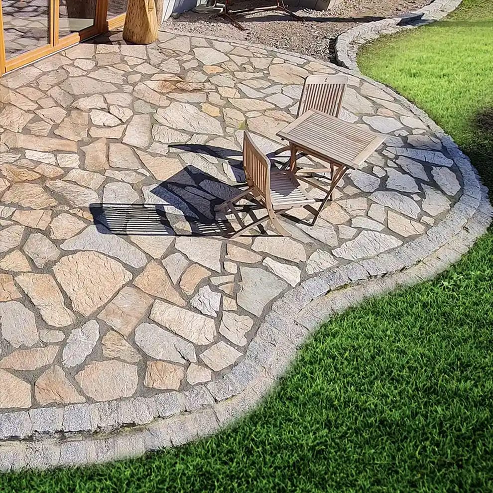 Gepflasterte Terrasse mit Gartenmöbeln und gepflegtem Rasen